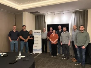 AllMax staff stand in front of a promotional banner at Operator's Edge Chicago